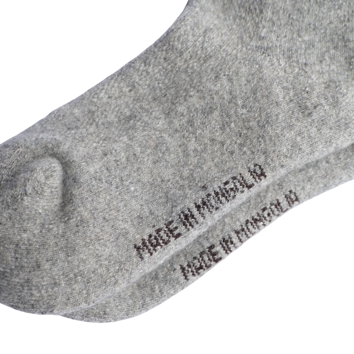 dessous de pied d'une chaussette en laine épaisse grise sur un fond blanc