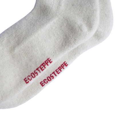 Gros plan sur une chaussette blanche en tricot portant le mot « ECOSTEPPE » imprimé en rouge sur le côté, présentée sur un fond blanc uni.
