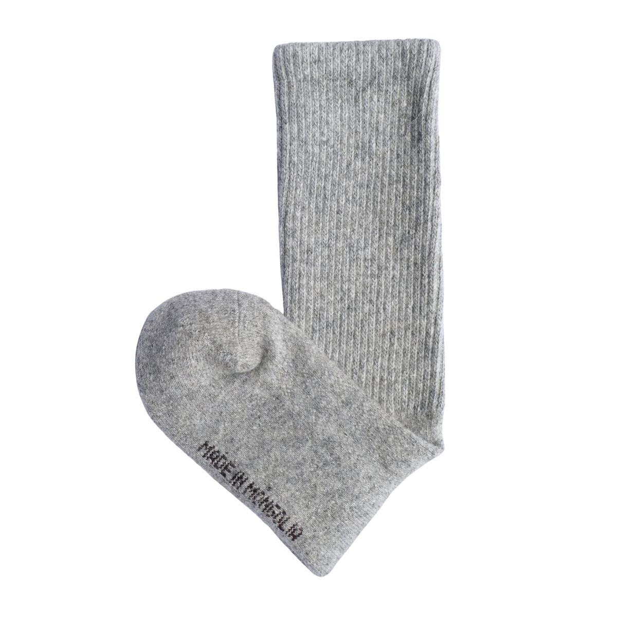 Une paire de chaussettes en maille côtelée gris clair : l'une est posée à plat pour montrer la pointe, tandis que l'autre est présentée à la verticale pour mettre en valeur la tige côtelée. La chaussette posée à plat porte l'inscription « MADE IN MONGOLIA » imprimée en noir.
