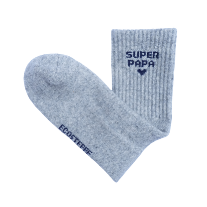 Une paire de chaussettes côtelées gris chiné clair sur fond blanc uni. L'une des chaussettes est posée à plat, laissant voir la pointe et le pied, tandis que l'autre est dressée verticalement, montrant le bord-côte.