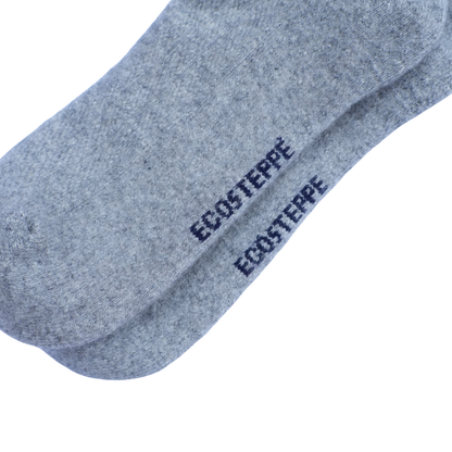 Gros plan sur une chaussette gris chiné portant le nom de la marque « ECOSTEPPE » imprimé en bleu marine, sur fond blanc uni.